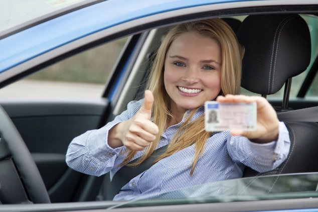 Donna al volante con patente in mano